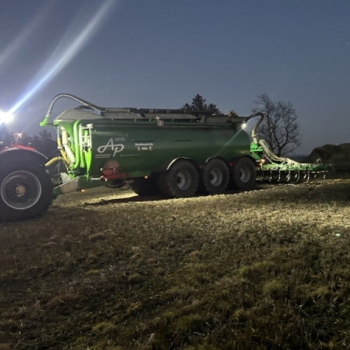 AP gyllevogn i arbejde på mark i mørke med lys på